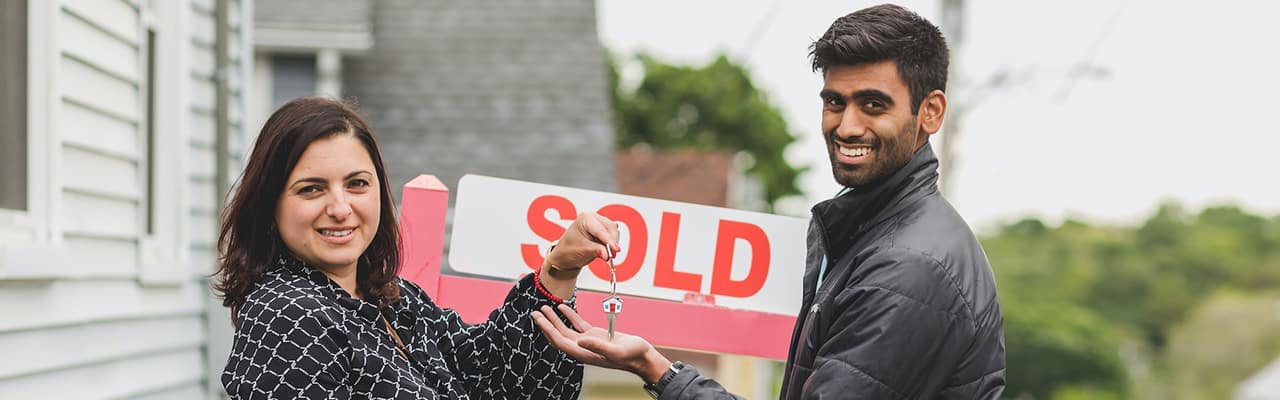 Realtor handing home buyer keys to just sold house
