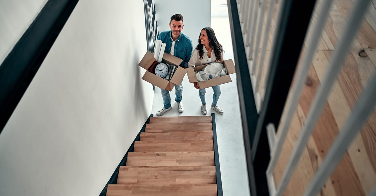 Two new homebuyers looking up a staircase